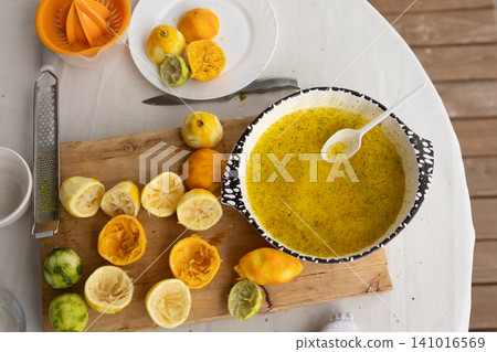 citrus juicer on kitchen counter with fresh squeezed juice bowl, top-down view of healthy eating preparation process in natural light setting, commercial food preparation. citrus juicer on kitchen counter with fresh squeezed juice bowl, top-down view of healthy eating preparation process in natural light setting, commercial food preparation. 141016569