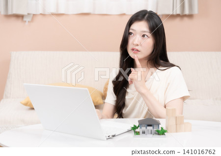 年輕女性使用筆記型電腦來考慮抵押貸款和購屋事宜。 年輕女性使用筆記型電腦來考慮抵押貸款和購屋事宜。 141016762