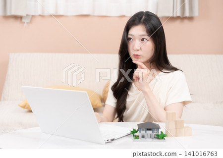 Young women using laptops to consider mortgages and home purchases. Young women using laptops to consider mortgages and home purchases. 141016763