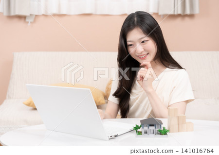 年輕女性使用筆記型電腦來考慮抵押貸款和購屋事宜。 年輕女性使用筆記型電腦來考慮抵押貸款和購屋事宜。 141016764