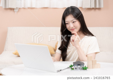 Young women using laptops to consider mortgages and home purchases. Young women using laptops to consider mortgages and home purchases. 141016765