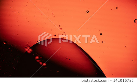 Close-up image featuring an orange background with a dark curved silhouette and scattered liquid droplets 141016785