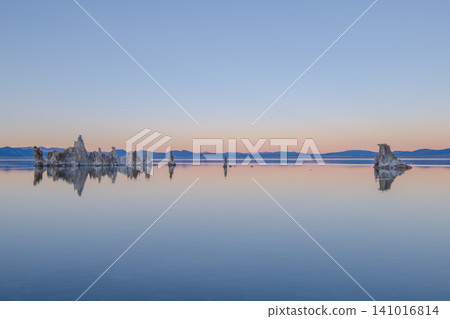 Tranquil mono lake reflection of tufa tower formations at sunset. calm water mirrors beautiful sky with distant Sierra Nevada mountains on horizon in California Tranquil mono lake reflection of tufa tower formations at sunset. calm water mirrors beautiful sky with distant Sierra Nevada mountains on horizon in California 141016814