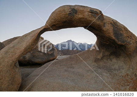 Serene natural rock arch frames majestic mountain landscape in Alabama Hill of California. view of Sierra Nevada creates peaceful feeling in nature 141016820