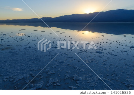 Serene sunset over Sierra Nevada mountain reflects on calm salt flat landscape. peaceful and vast natural scene in Death Valley showing beautiful scenery 141016826