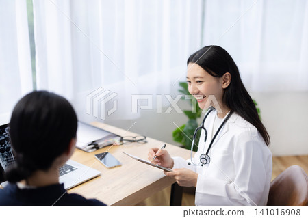 A young Japanese female doctor examining a patient A young Japanese female doctor examining a patient 141016908