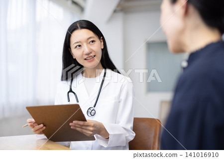 A young Japanese female doctor examining a patient A young Japanese female doctor examining a patient 141016910