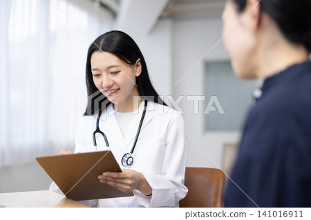 A young Japanese female doctor examining a patient A young Japanese female doctor examining a patient 141016911