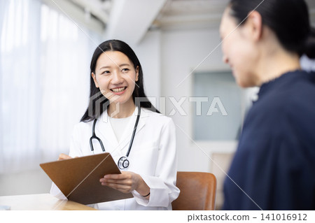 A young Japanese female doctor examining a patient A young Japanese female doctor examining a patient 141016912