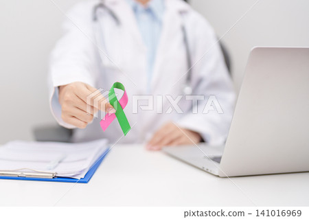Doctor giving purple and green ribbon to patient for concept of October Metastatic Breast Cancer Awareness month, National Cancer Survivors Month and Pink October Healthcare and February world cancer Doctor giving purple and green ribbon to patient for concept of October Metastatic Breast Cancer Awareness month, National Cancer Survivors Month and Pink October Healthcare and February world cancer 141016969