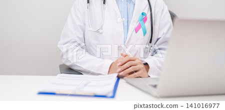 doctor using laptop and report notes on notebook. blue and pink ribbon concept of October male Breast Cancer Awareness month, National Cancer Survivors Month and Pink October Healthcare doctor using laptop and report notes on notebook. blue and pink ribbon concept of October male Breast Cancer Awareness month, National Cancer Survivors Month and Pink October Healthcare 141016977
