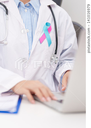 doctor using laptop and report notes on notebook. blue and pink ribbon concept of October male Breast Cancer Awareness month, National Cancer Survivors Month and Pink October Healthcare doctor using laptop and report notes on notebook. blue and pink ribbon concept of October male Breast Cancer Awareness month, National Cancer Survivors Month and Pink October Healthcare 141016979