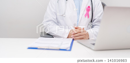 Professional doctor wearing lab coat using laptop and taking report notes on notebook for Breast Cancer Awareness month, World Cancer Day, National Cancer Survivors Month and Pink October in hospital Professional doctor wearing lab coat using laptop and taking report notes on notebook for Breast Cancer Awareness month, World Cancer Day, National Cancer Survivors Month and Pink October in hospital 141016983
