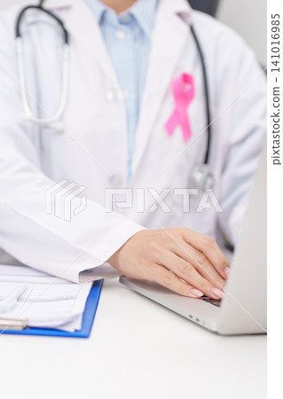 Professional doctor wearing lab coat using laptop and taking report notes on notebook for Breast Cancer Awareness month, World Cancer Day, National Cancer Survivors Month and Pink October in hospital Professional doctor wearing lab coat using laptop and taking report notes on notebook for Breast Cancer Awareness month, World Cancer Day, National Cancer Survivors Month and Pink October in hospital 141016985