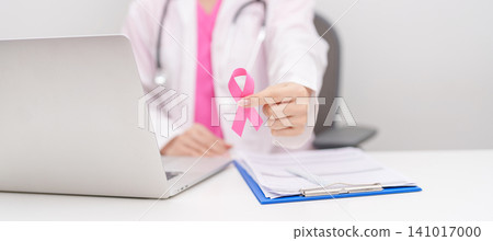 Doctor wearing lab coat giving pink ribbon to patient for Breast Cancer Awareness month, World Cancer Day, National Cancer Survivors Month, Pink October and Women Health empathy concept in hospital Doctor wearing lab coat giving pink ribbon to patient for Breast Cancer Awareness month, World Cancer Day, National Cancer Survivors Month, Pink October and Women Health empathy concept in hospital 141017000