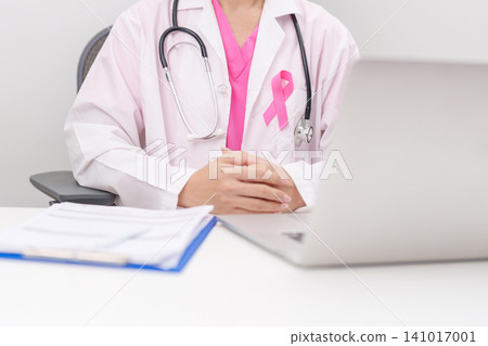 Professional doctor wearing lab coat using laptop and taking report notes on notebook for Breast Cancer Awareness month, World Cancer Day, National Cancer Survivors Month and Pink October in hospital Professional doctor wearing lab coat using laptop and taking report notes on notebook for Breast Cancer Awareness month, World Cancer Day, National Cancer Survivors Month and Pink October in hospital 141017001