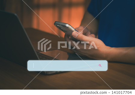 Man using smartphone and laptop with search bar for AI data browsing and SEO internet technology. Digital marketing and online information search engine concept on dark background. 141017704