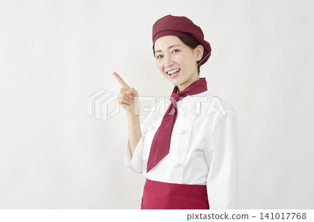 A female pastry chef points to the left. A female pastry chef points to the left. 141017768