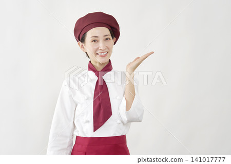 A female pastry chef points to the right with her palm. A female pastry chef points to the right with her palm. 141017777
