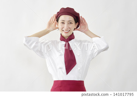 一位女性糕點師/麵包師/咖啡館員工，擺出聆聽的姿勢，背景為白色。 141017795