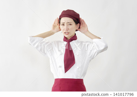 Female pastry chef/baker/cafe employee, in a listening pose, against a white background. Female pastry chef/baker/cafe employee, in a listening pose, against a white background. 141017796