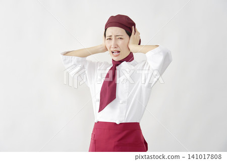 Female pastry chef/baker/cafe employee covering her ears against a white background. Female pastry chef/baker/cafe employee covering her ears against a white background. 141017808
