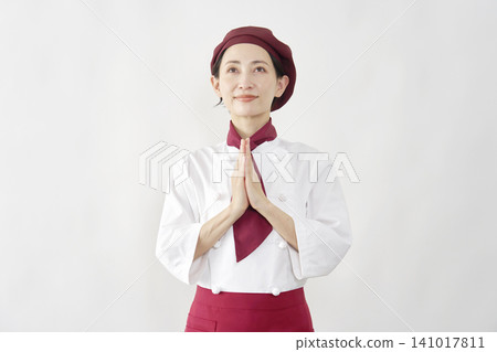 Female pastry chef/baker/cafe employee praying against a white background. Female pastry chef/baker/cafe employee praying against a white background. 141017811