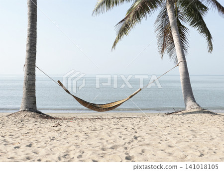 A bamboo hammock hangs under a coconut tree on the beach by the sea. A bamboo hammock hangs under a coconut tree on the beach by the sea. 141018105