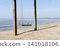 A wooden hanging swing on the beach by the sea. 141018106