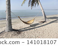 A bamboo hammock hangs under a coconut tree on the beach by the sea. 141018107