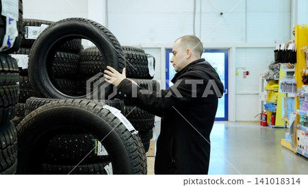 Professional mechanic checking winter studded tires, selecting appropriate rubber for vehicle safety during harsh seasonal driving conditions Professional mechanic checking winter studded tires, selecting appropriate rubber for vehicle safety during harsh seasonal driving conditions 141018314