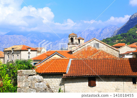 Old town with medieval houses and mountain, Herceg Novi, Montenegro. Topic of summer vacation, travel. Red-tiled rooftops in historic streets of Herceg Novi resting beneath towering mountain slopes Old town with medieval houses and mountain, Herceg Novi, Montenegro. Topic of summer vacation, travel. Red-tiled rooftops in historic streets of Herceg Novi resting beneath towering mountain slopes 141018455