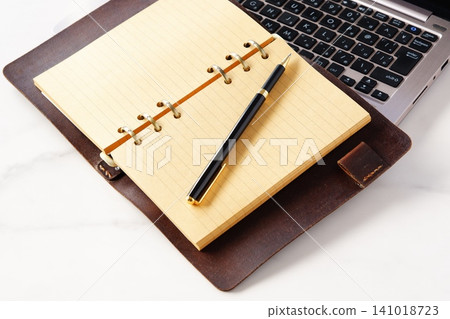 Image of a ring-type system organizer open and doing desk work on a laptop 141018723