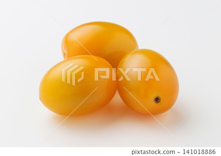 Three yellow cherry tomatoes placed together against a white background. Three yellow cherry tomatoes placed together against a white background. 141018886