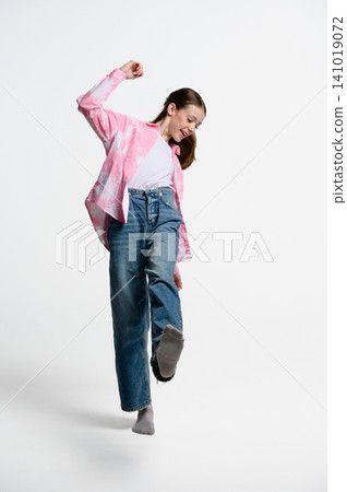 Portrait of playful teenage girl balancing on one foot and kicking leg forward. Portrait of playful teenage girl balancing on one foot and kicking leg forward. 141019072