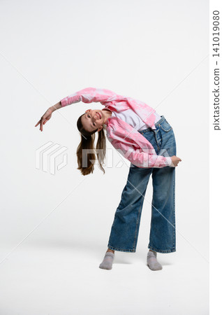 Full length portrait of teenage girl performing side bend stretch exercise. 141019080