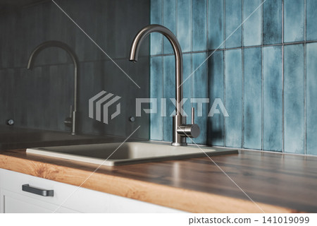 Modern kitchen sink with stainless steel faucet and blue ceramic tile backsplash Modern kitchen sink with stainless steel faucet and blue ceramic tile backsplash 141019099