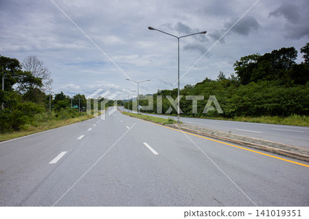 Empty road, green forest, cloudy sky, highway, empty lane Empty road, green forest, cloudy sky, highway, empty lane 141019351