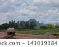 Rural landscape with truck dirt road green field mountain cloudy sky tree line farm open field countryside construction site 141019384