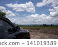 Car side view rural road cloudy sky landscape field mountain dirt road black vehicle countryside horizon 141019389