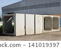 Concrete box culvert segments on industrial site, large precast concrete structure outdoors near warehouse wall 141019397