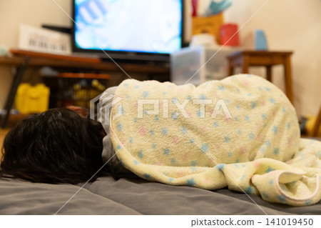 The back view of a child lying down at night while watching TV 141019450