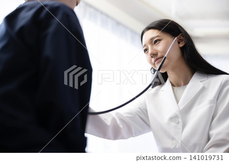 一位年輕的日本女醫生正在使用聽診器進行檢查。 141019731
