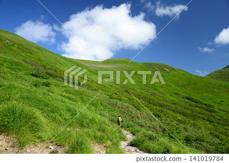 Mount Gassan in August: Hikers heading towards the blue sky through the green mountains. Mount Gassan in August: Hikers heading towards the blue sky through the green mountains. 141019784