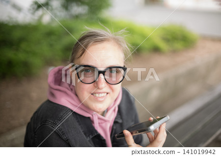 Smiling woman using smartphone while sitting Smiling woman using smartphone while sitting 141019942