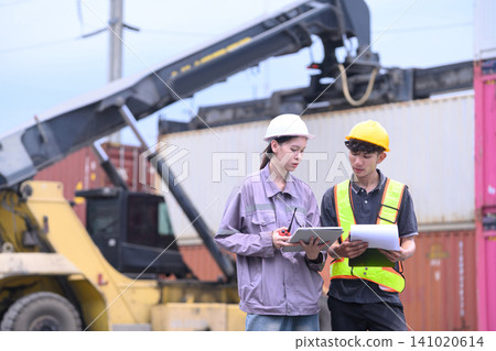 Two workers review shipment data at a bustling port Two workers review shipment data at a bustling port 141020614
