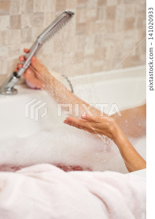 Woman's hands catching water from a shower head during a relaxing bubble bath, showing skincare and hygiene Woman's hands catching water from a shower head during a relaxing bubble bath, showing skincare and hygiene 141020933