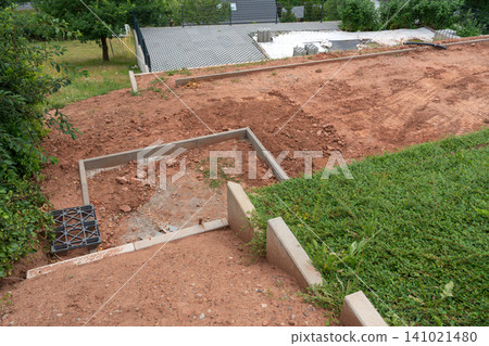 Aerial view of a construction site in a residential area, showcasing the preparation phase with concrete blocks, dirt, and grass, set against a backdrop of brown and green tones, ideal. Aerial view of a construction site in a residential area, showcasing the preparation phase with concrete blocks, dirt, and grass, set against a backdrop of brown and green tones, ideal. 141021480