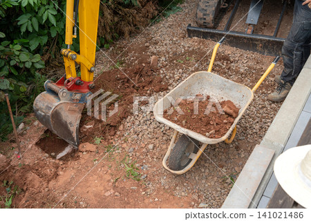 excavator bucket actively digs through soil and rocks on a construction site, offering a side view of the active work environment with vibrant yellow and red tones, natural lighting. excavator bucket actively digs through soil and rocks on a construction site, offering a side view of the active work environment with vibrant yellow and red tones, natural lighting. 141021486