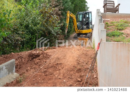 construction workers actively excavating at a residential site, using an excavator and wheelbarrows, surrounded by concrete blocks and dirt, ground level view, brown and green tones, ideal. construction workers actively excavating at a residential site, using an excavator and wheelbarrows, surrounded by concrete blocks and dirt, ground level view, brown and green tones, ideal. 141021488
